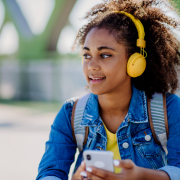 Multiracial,Teenage,Girl,With,Backpack,,Headphones,And,Smartphone,Resting,After