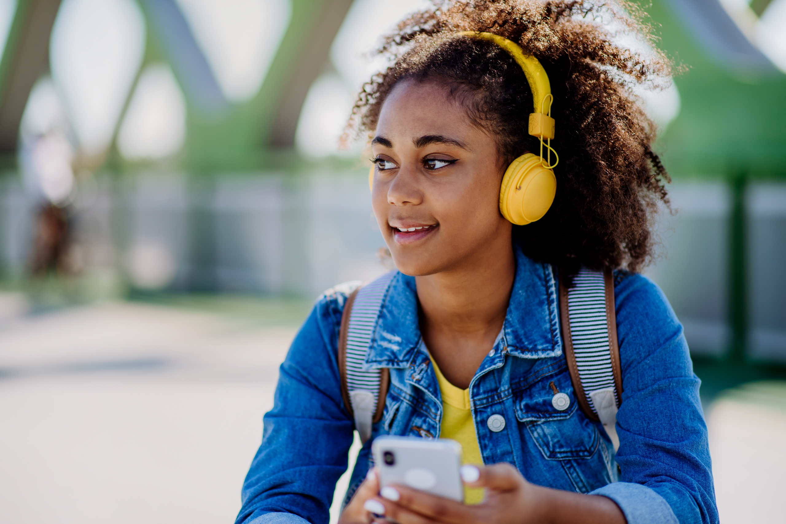 Multiracial,Teenage,Girl,With,Backpack,,Headphones,And,Smartphone,Resting,After